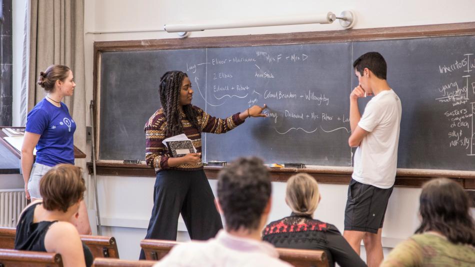 A group of students standing and sitting around a blackboard