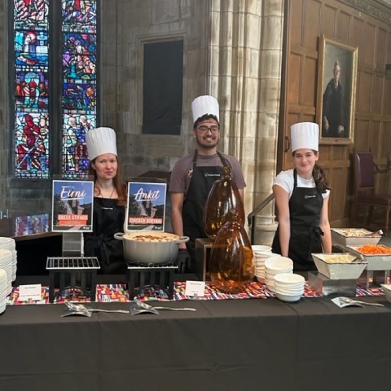 Three students in chef hats at a buffet table
