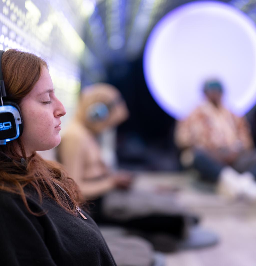 A female student wearing headphones and meditating.