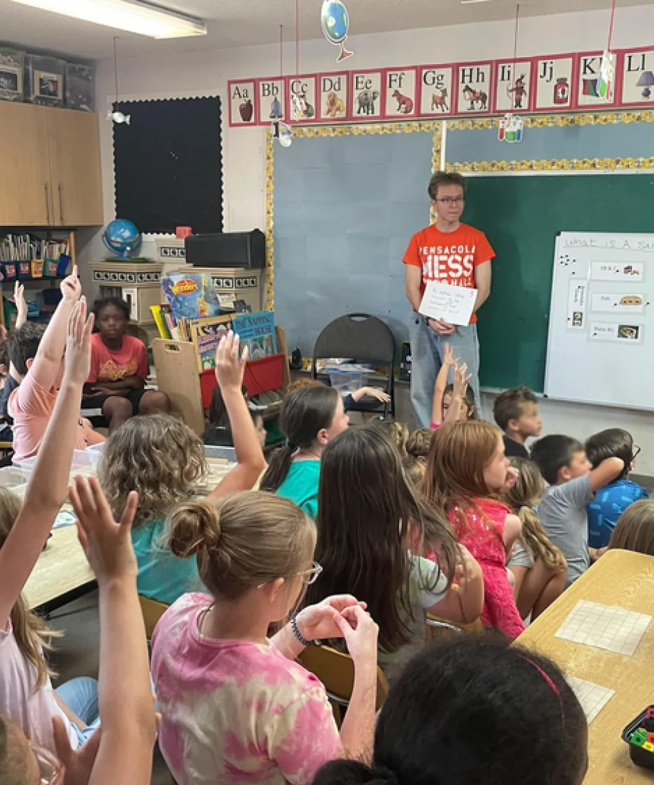 A student in a classroom volunteering