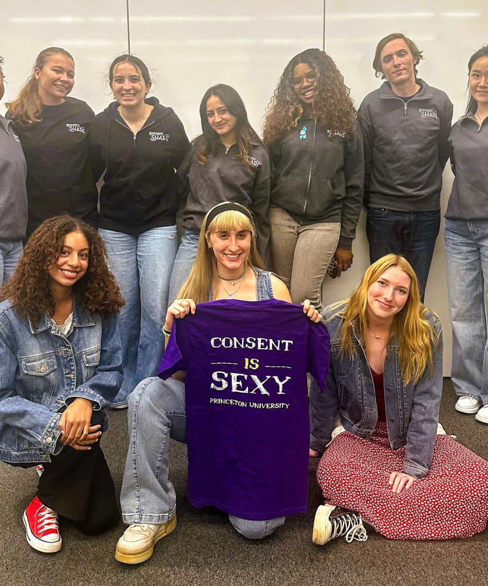 Share peers holding a shirt that reads "consent is sexy"