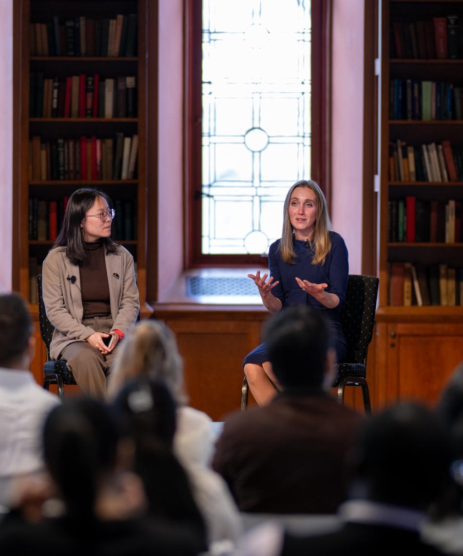 Two graduate students talking on a panel