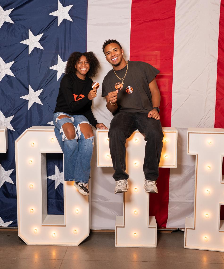 Students sitting on a sign that spells out Vote
