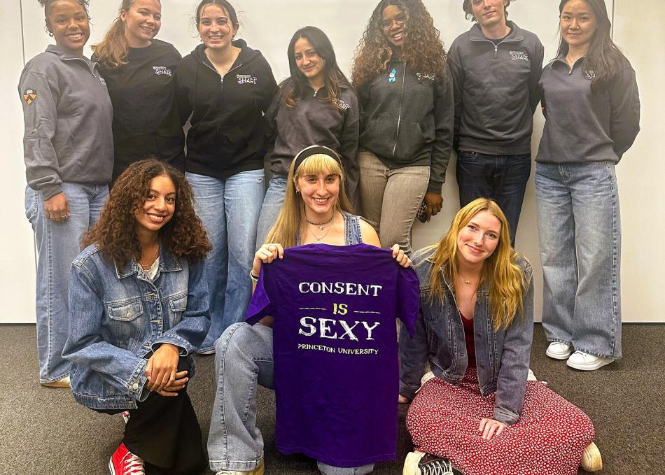 Share peers holding a shirt that reads "consent is sexy"