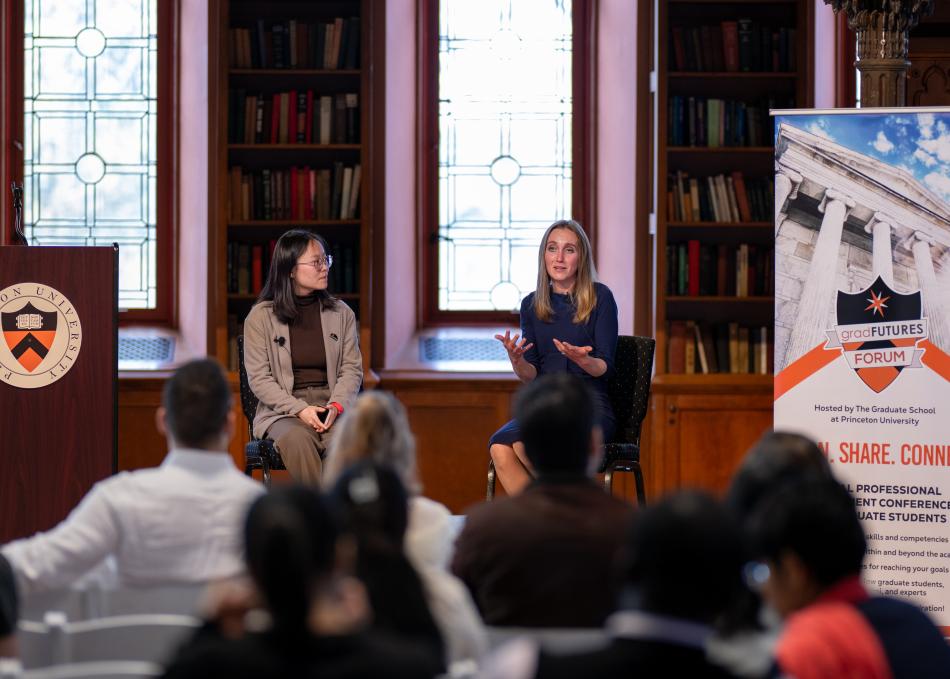 Two graduate students talking on a panel
