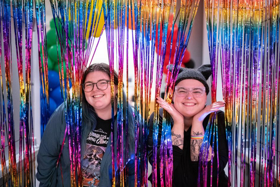 Staff members posing with a rainbow backdrop 