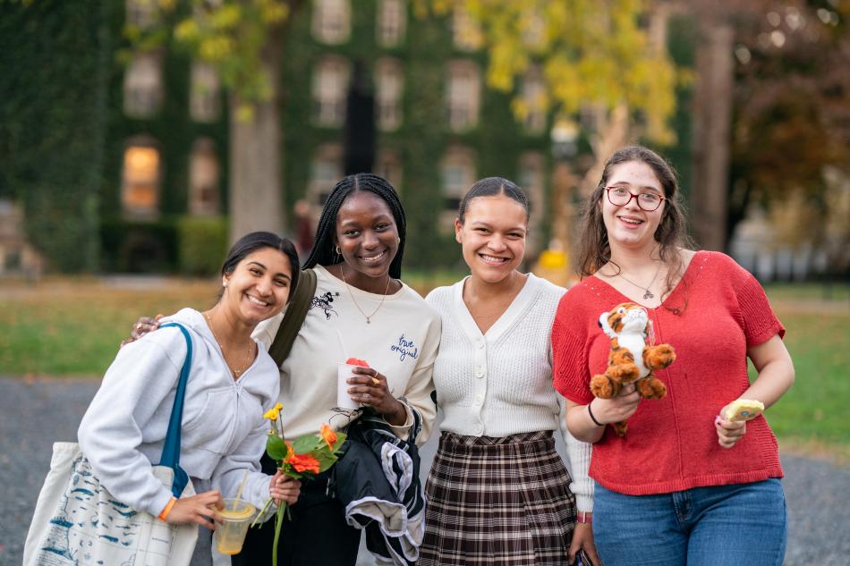 Students smiling with flowers and a tiger plush